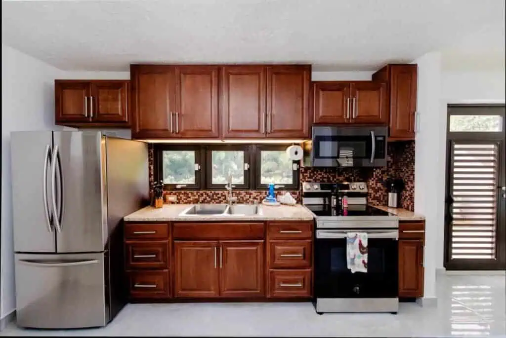 Kitchen with wooden cabinets, stainless steel refrigerator, and black appliances.