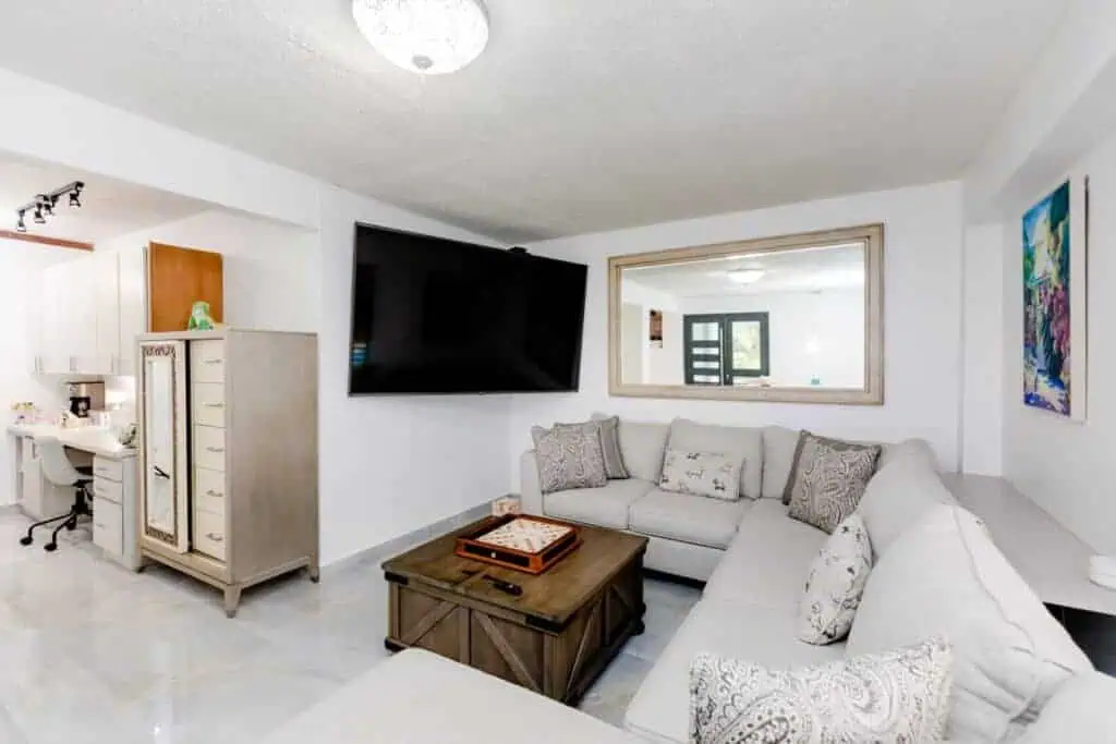 Bright living room with a large wall-mounted TV and a cozy sectional sofa.