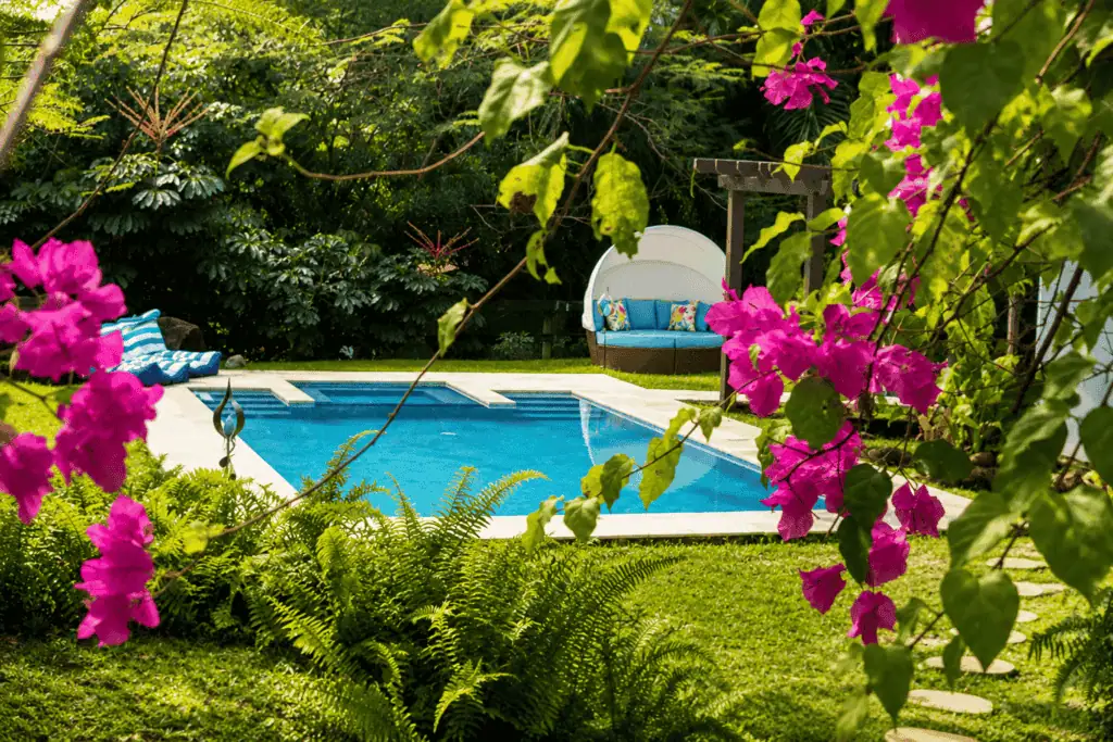 Serene backyard with swimming pool, lush greenery, and outdoor seating at Casa Encanto.