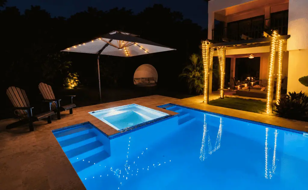 Night view of a luxury villa with illuminated pool and outdoor seating area.