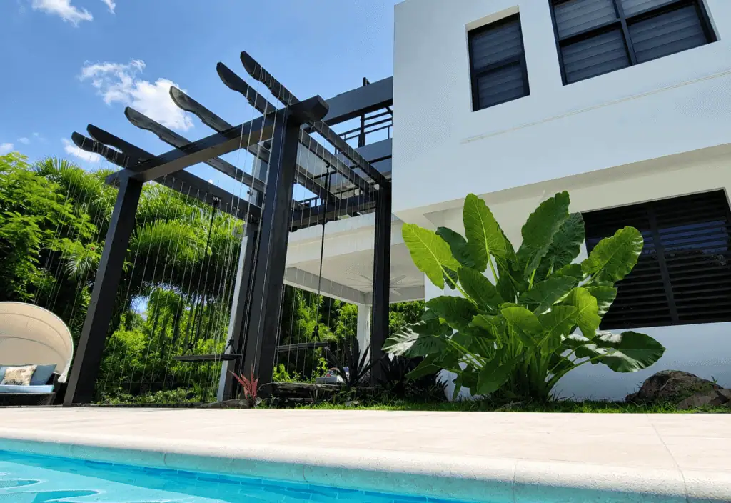 Contemporary house exterior with pool, lush greenery, and modern design features.