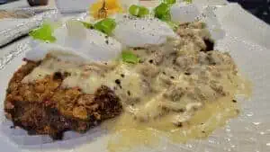 Crispy fried chicken topped with poached eggs and green onions, served with mushroom sauce.