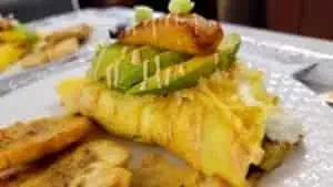 Breakfast burrito with avocado, banana, and cheese on a plate.
