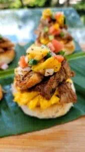 Close-up of Puerto Rican mofongo with meat and vegetable toppings on a banana leaf.